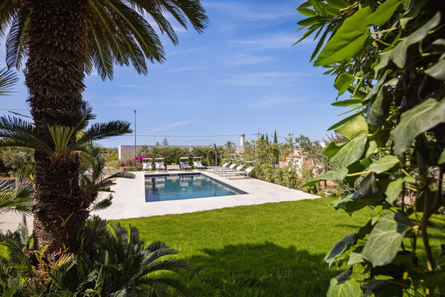 A serene luxury villa in Sicily featuring a private pool, surrounded by lush greenery and sun loungers.