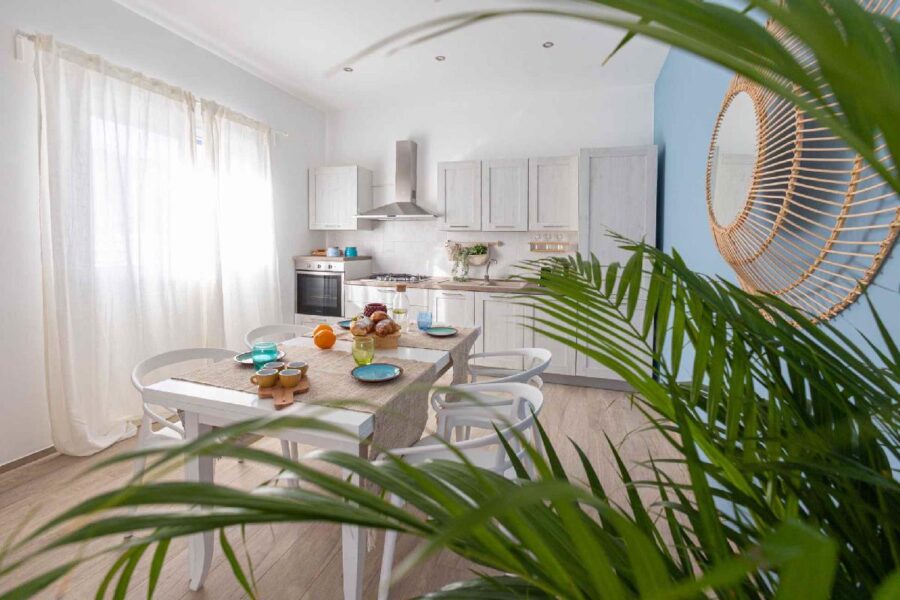 Bright and modern kitchen at Villa Blue Oasis, a stunning Sicily luxury villa, featuring elegant white cabinetry, natural light, and a cozy dining setup.