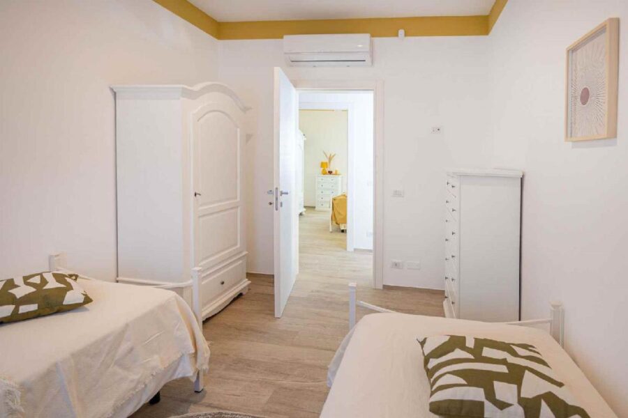 Bright and minimal twin bedroom at Villa Blue Oasis, a stunning Sicily villa with a pool, featuring elegant white furnishings and warm accents.