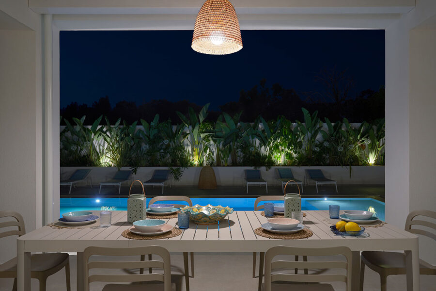 Dining table set up by the pool for an evening meal at Azure Essence villa, Sicily