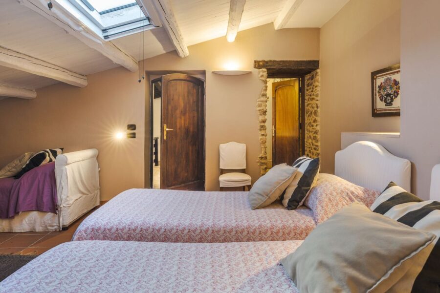Twin bedroom with sloped ceiling, skylight, and exposed beams in a cozy rustic suite at Villa Selvira, one of the top Sicily luxury villas with pool.