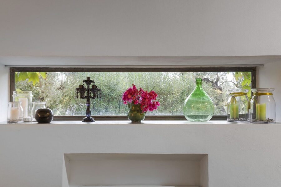 Window shelf at Villa Selvira, a Sicily luxury villa, decorated with candles, glass bottles, and fresh flowers.