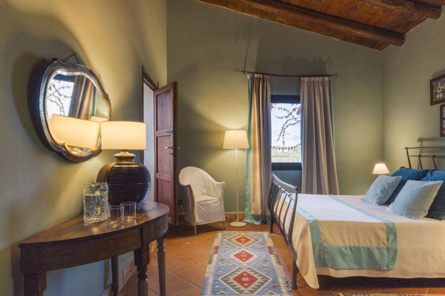 Warmly lit bedroom with rustic decor and countryside view at Villa Selvira, Sicily luxury villa