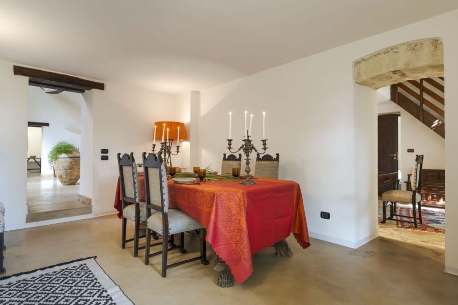 Warm dining area in Villa Selvira, a Sicily luxury villa, featuring antique chairs, candelabras, and a vibrant table setting.