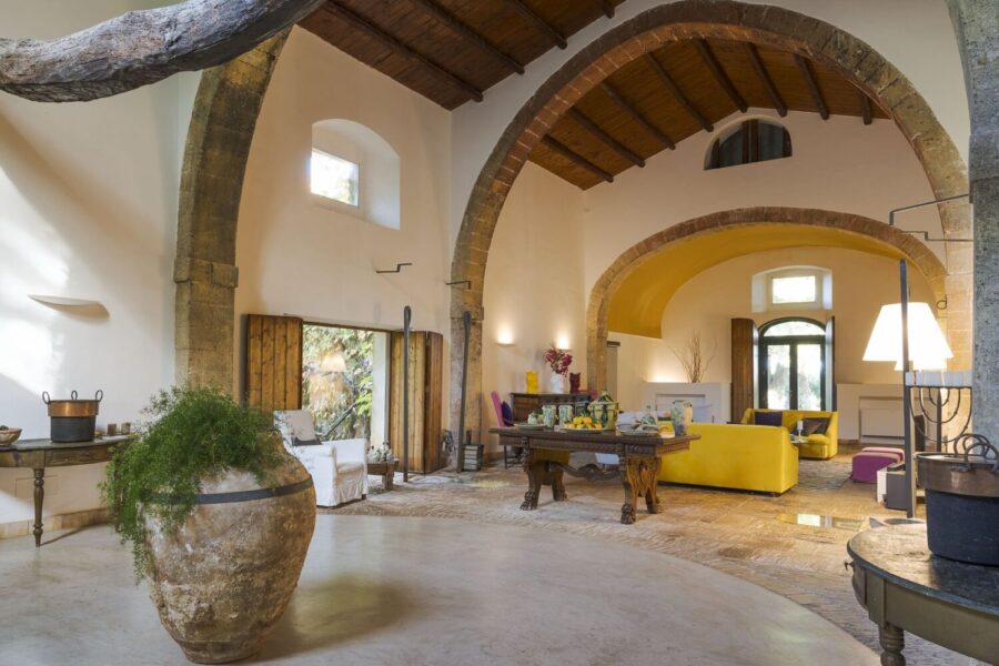 Spacious living room at Villa Selvira, a Sicily luxury villa, with vaulted ceilings, stone arches, and eclectic décor.