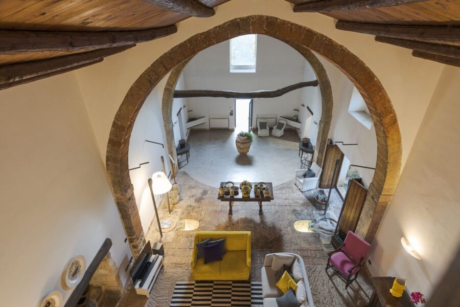 Overhead view of Villa Selvira’s grand living area with arched stone structure, rustic floors, and eclectic furniture – a unique Sicily villa with pool.