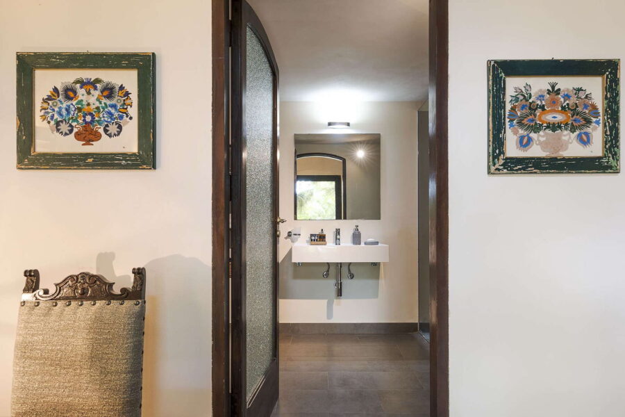 Interior view of Villa Selvira, a Sicily luxury villa, showing a bright bathroom with artistic wall décor and antique touches.