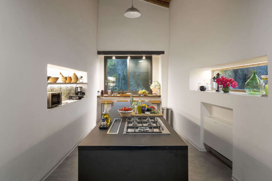Modern Sicilian kitchen at Villa Selvira with fresh vegetables, olive oil, and a scenic garden view – perfect for luxury stays in Sicily villas with pool.